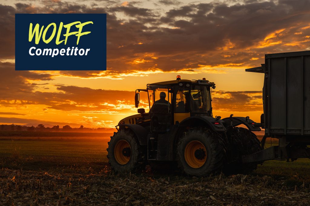 A construction vehicle is silhouetted against the sunset.