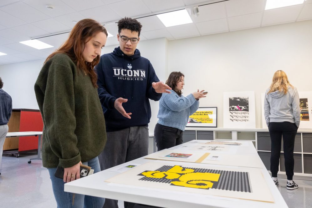 Students in professor Enrique Figueredo's Printmaking Workshop class (ART 3530) observe and discuss some of the artwork put on display by Assistant Curator and Academic Liaison for University Learning Amanda Douberley in the Benton Museum of Art's new Education Space