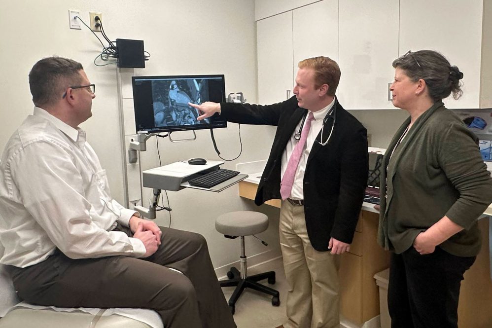 patient and two clinicians discussing image on screen in exam room