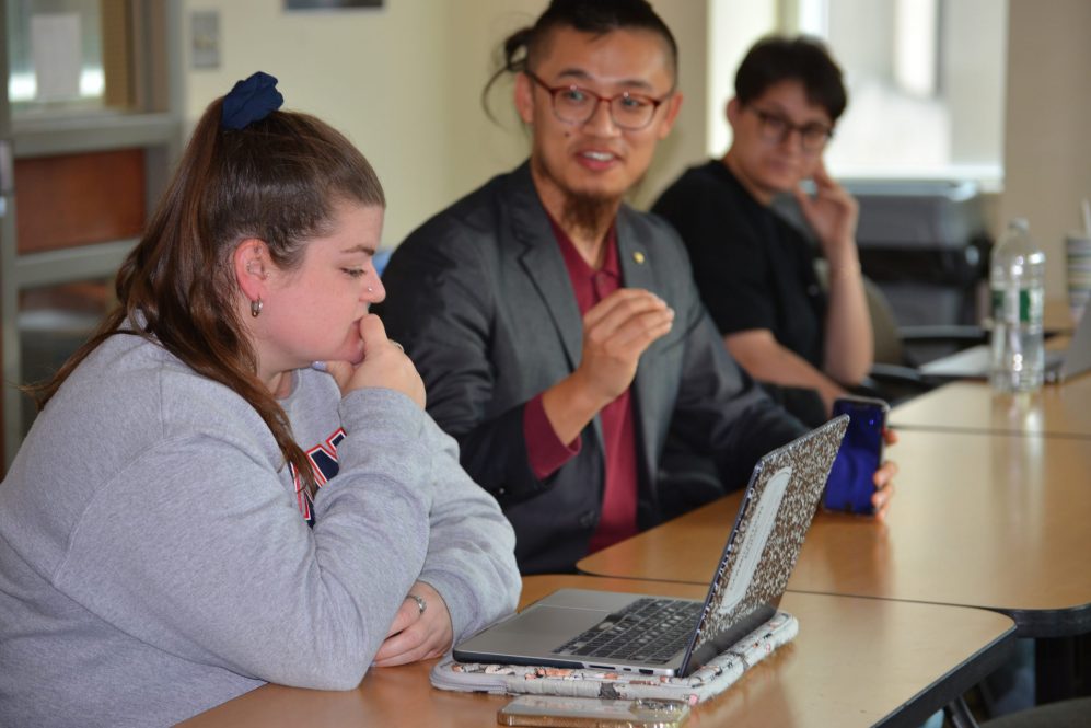 Faculty member speaks with student at table.