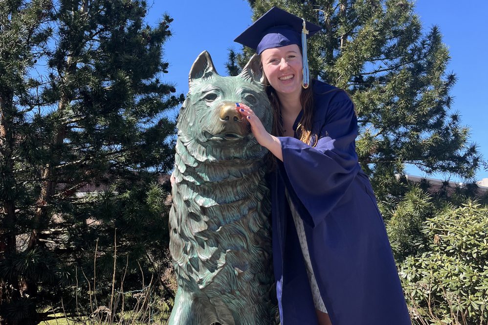 Female student in cap and gown by Jonathan statue.