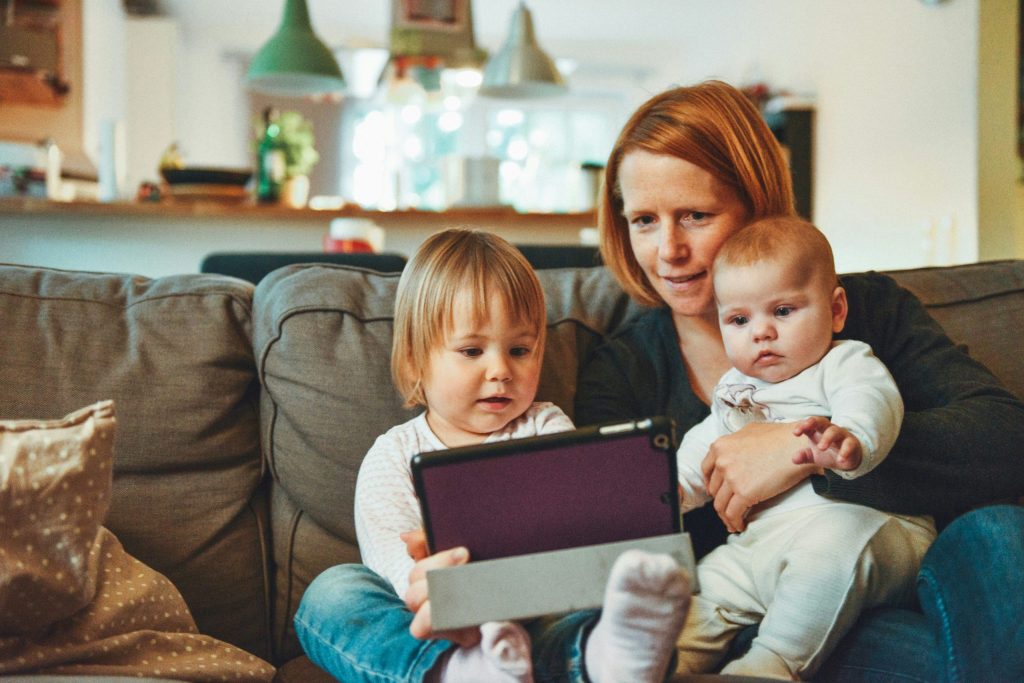 A parent and two young children sit together on a couch.