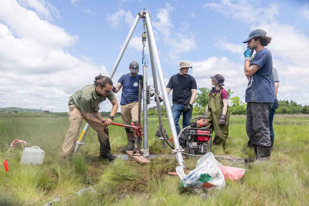 William Ouimet, associate professor of geography at UConn, and a team of students collect a soil core on Grannis Island in New Haven with a 24-foot-long pipe.