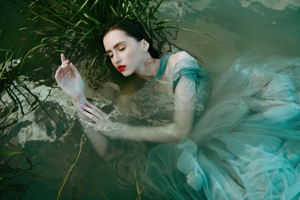 A bewitching water nymph is lying in the water of the river.