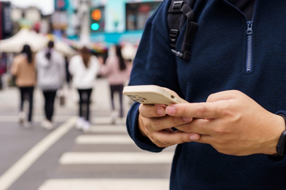 Man in a navy half-zip sweater using a smartphone