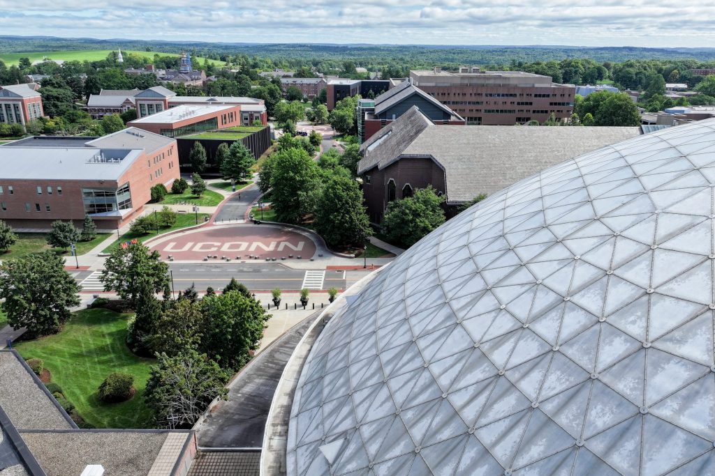 An aerial view of the UConn wordmark on Fairfield Way on a sunny day in Storrs