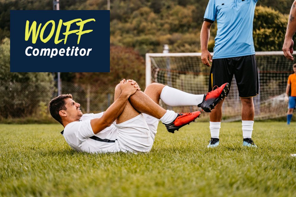 A soccer player on the ground, clutching his knee in agony.