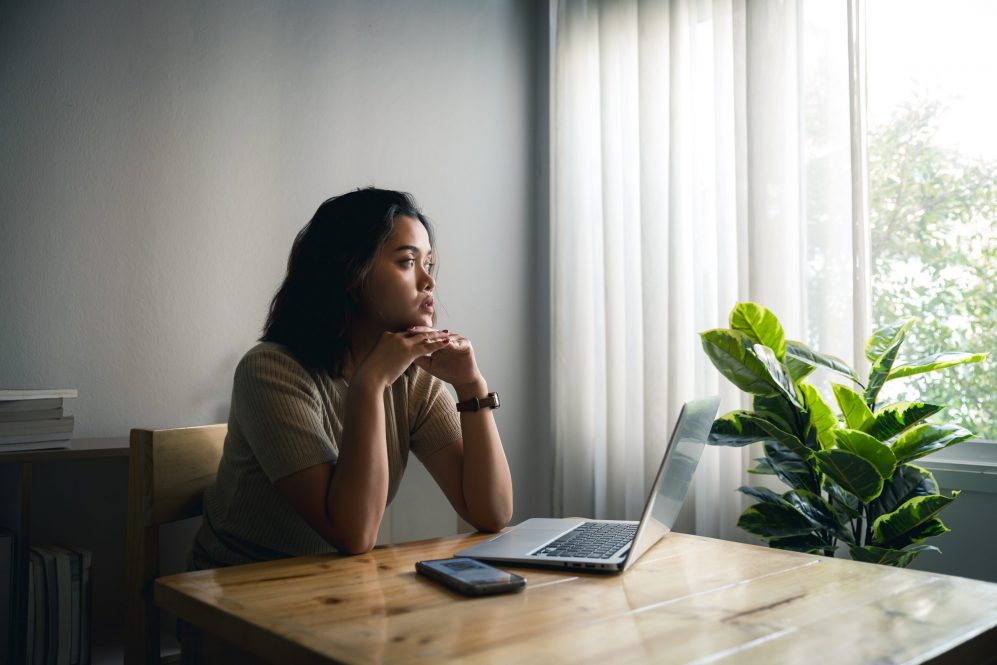 Confused concerned young woman getting problems with mobile phone while working at home, feeling stressed, frustrated