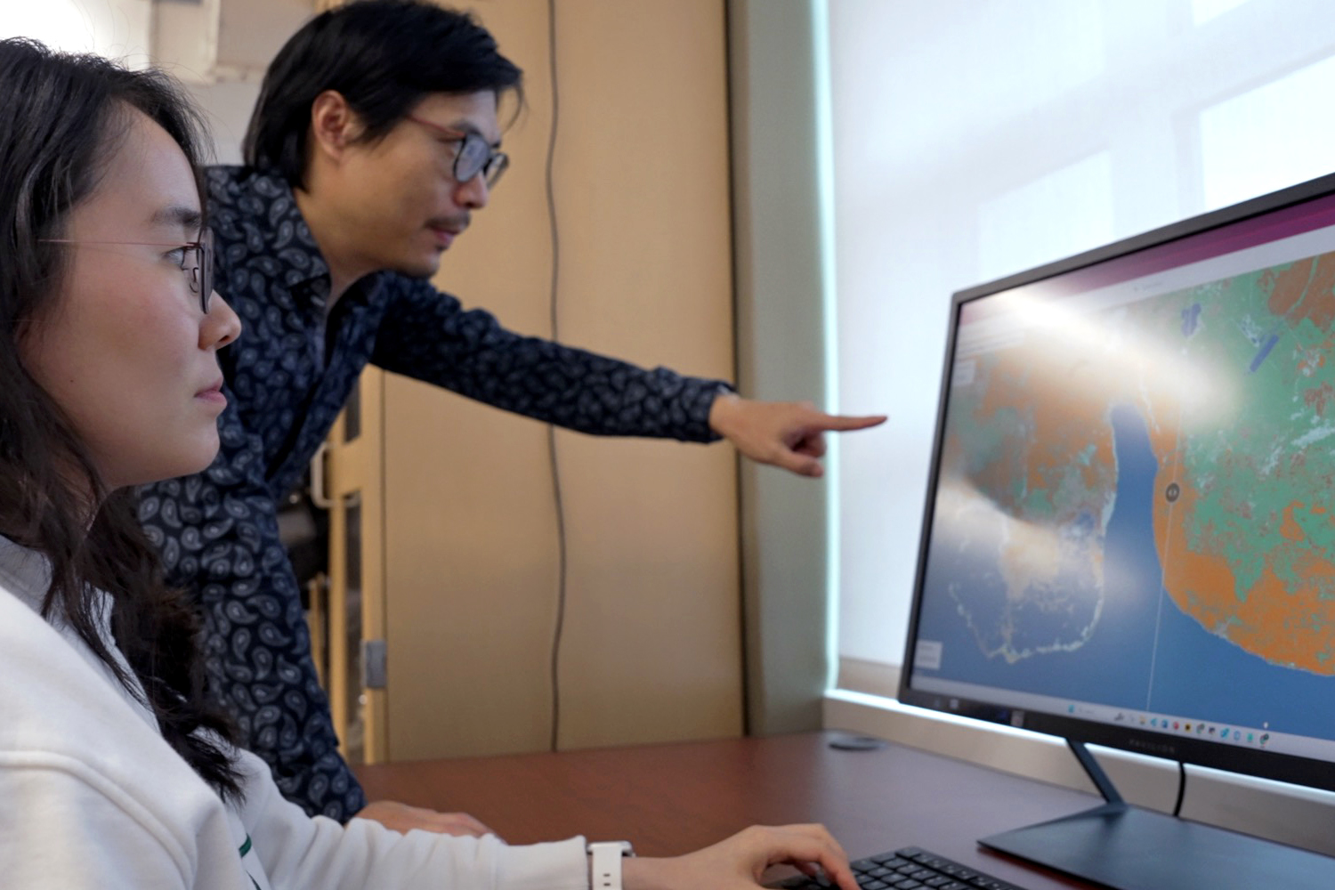 Man and woman researcher looking at data on a computer