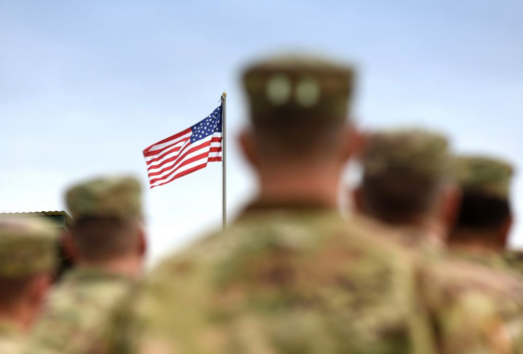 American Soldiers standing in front of thr US Flag.