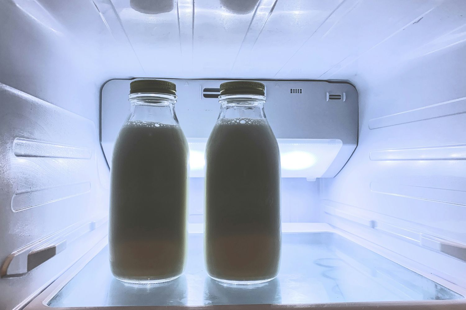 Two glass containers of mil in a refrigerator