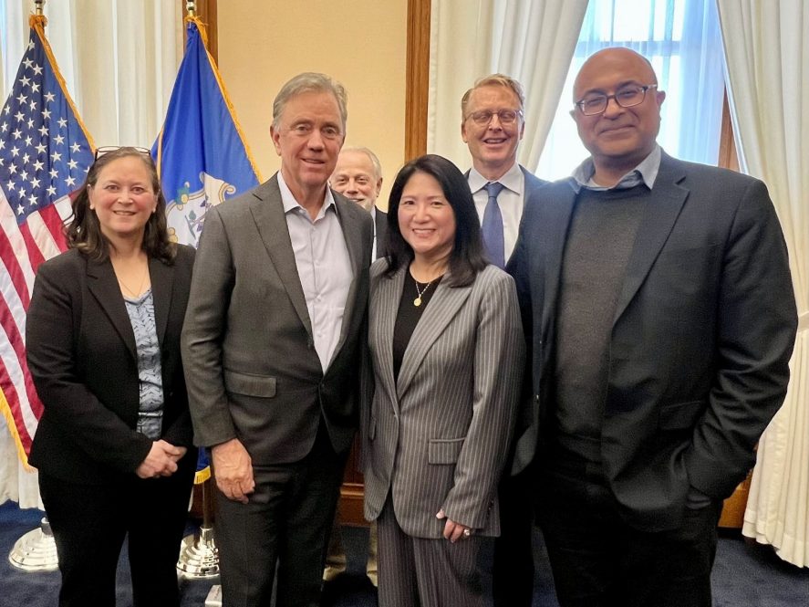 A posed photo of Governor Ned Lamont surrounded by five UConn Law alumni and faculty members who have worked on the bill.